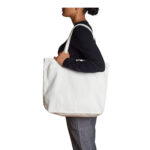Side view of a female model wearing the AS Colour Shoulder Tote Bag in colour cream